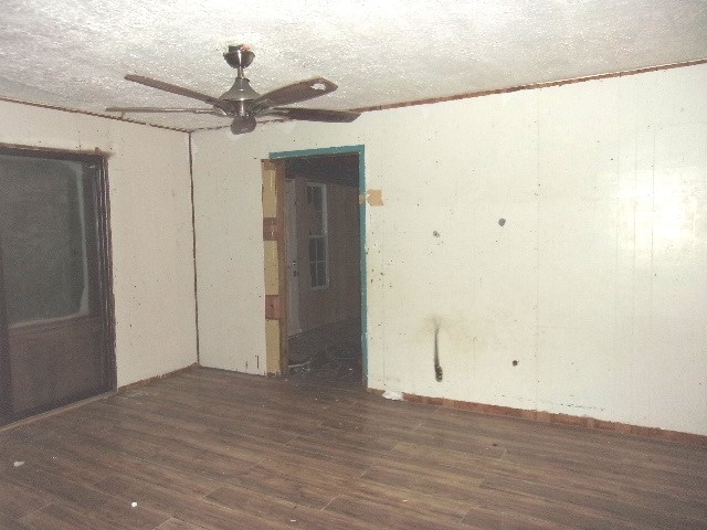 unfurnished room featuring ceiling fan, dark hardwood / wood-style floors, and a textured ceiling