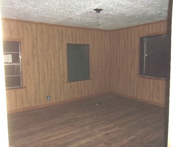 spare room featuring dark wood-type flooring and a textured ceiling