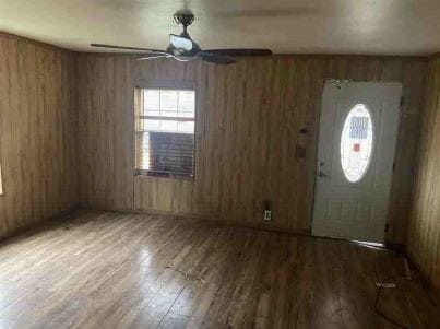 foyer featuring wood-type flooring, ceiling fan, and wood walls