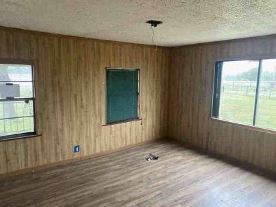 empty room featuring hardwood / wood-style floors, wooden walls, and a textured ceiling