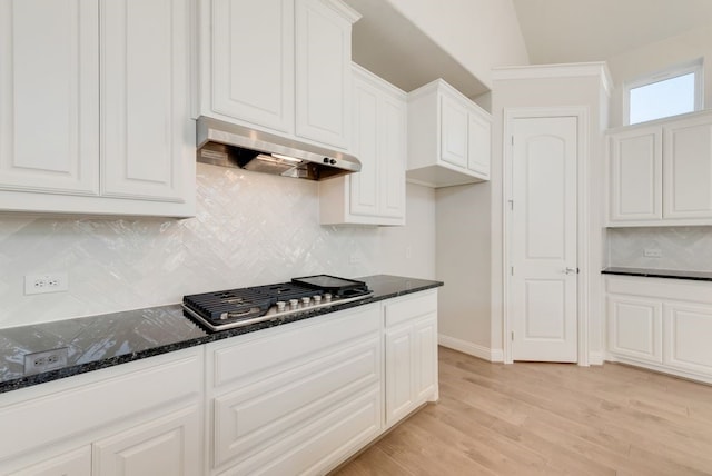 kitchen with ventilation hood, white cabinetry, stainless steel gas cooktop, and dark stone counters