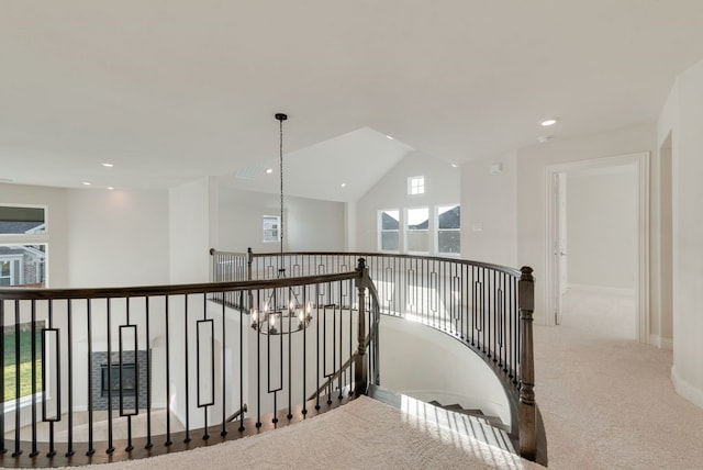 hall featuring plenty of natural light, lofted ceiling, carpet floors, and an inviting chandelier