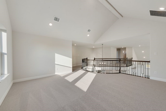 carpeted spare room with beamed ceiling and high vaulted ceiling