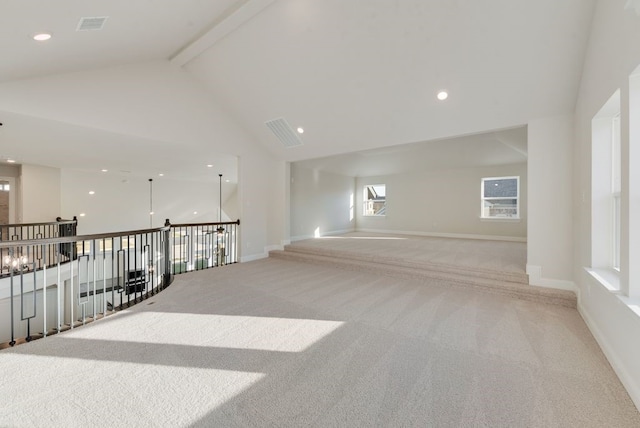 carpeted empty room with beamed ceiling and high vaulted ceiling