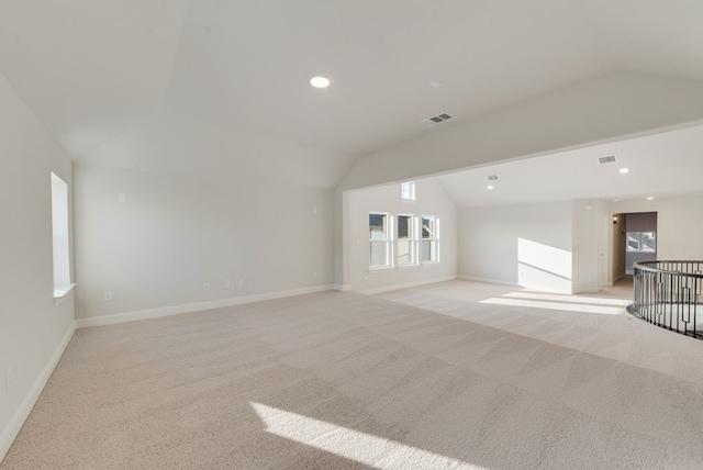 unfurnished living room featuring a healthy amount of sunlight, light colored carpet, and lofted ceiling