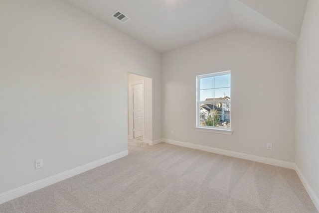 spare room with light carpet and lofted ceiling