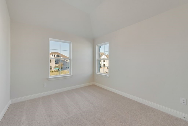 carpeted spare room with vaulted ceiling