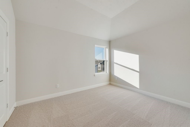 carpeted spare room with lofted ceiling