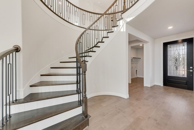 foyer entrance featuring recessed lighting, baseboards, a high ceiling, and wood finished floors