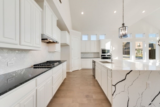 kitchen with white cabinets, pendant lighting, stainless steel appliances, and dark stone counters