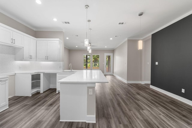 kitchen with backsplash, ornamental molding, sink, white cabinetry, and hanging light fixtures