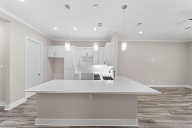 kitchen with light stone counters, white cabinets, and pendant lighting