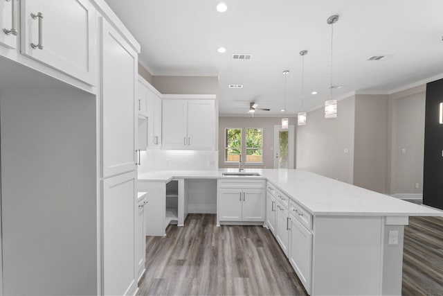 kitchen featuring light stone countertops, ornamental molding, ceiling fan, white cabinets, and hanging light fixtures