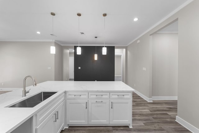 kitchen with pendant lighting, sink, light stone countertops, ornamental molding, and white cabinetry