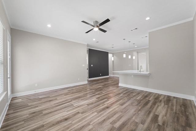 unfurnished living room featuring hardwood / wood-style flooring, plenty of natural light, ceiling fan, and ornamental molding