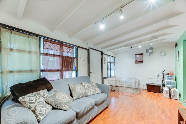 living room featuring rail lighting, hardwood / wood-style flooring, and vaulted ceiling with beams