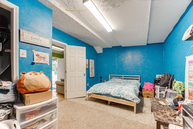 bedroom featuring a textured ceiling, vaulted ceiling, and carpet floors