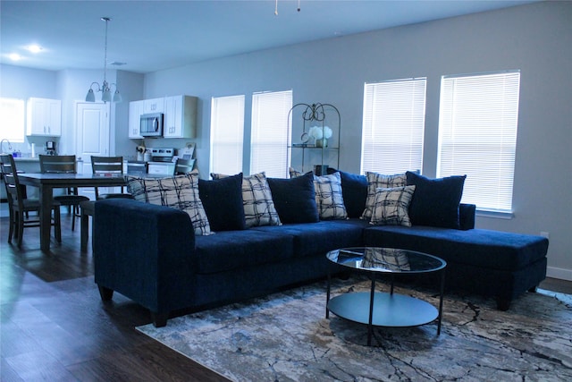 living room featuring dark wood-type flooring, a notable chandelier, and a healthy amount of sunlight