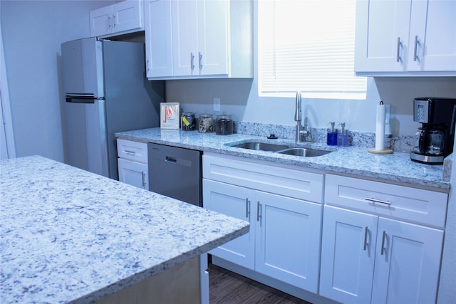 kitchen with dark wood-type flooring, sink, light stone countertops, white cabinets, and appliances with stainless steel finishes