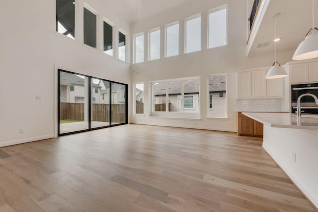 unfurnished living room featuring baseboards, a sink, and light wood finished floors