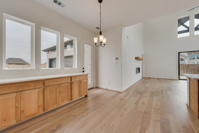 dining area with baseboards, light wood-type flooring, visible vents, and a notable chandelier