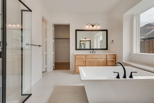 full bathroom with a stall shower, a soaking tub, tile patterned flooring, a spacious closet, and vanity