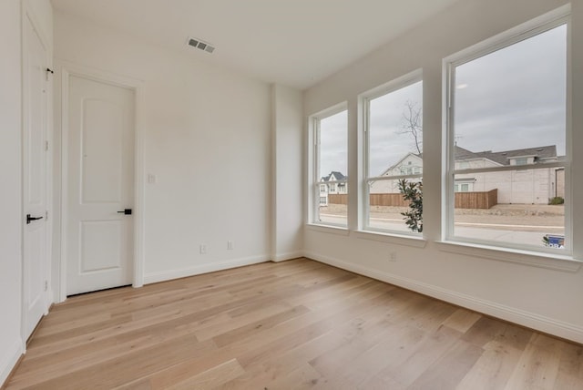 spare room featuring baseboards, visible vents, and light wood finished floors