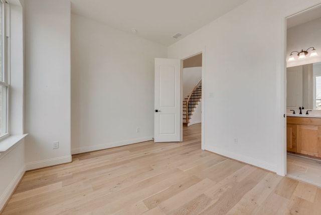 empty room featuring a sink, light wood-style flooring, and baseboards