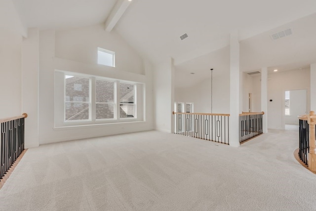 carpeted empty room with visible vents, high vaulted ceiling, and beamed ceiling