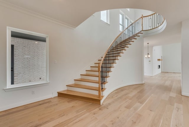 staircase featuring a towering ceiling, baseboards, and wood finished floors