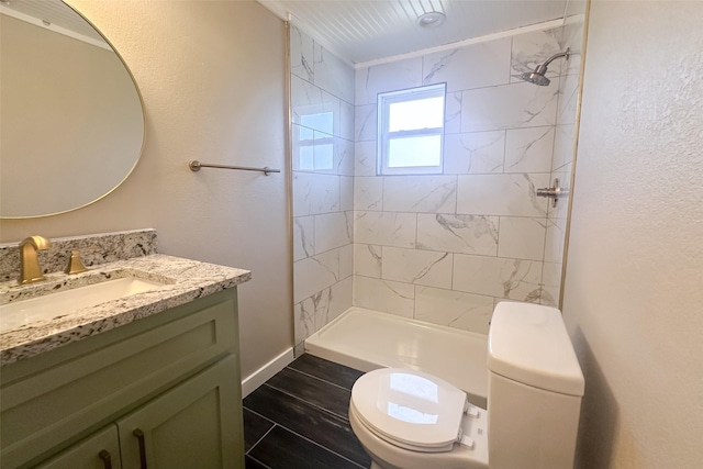 bathroom with tiled shower, hardwood / wood-style floors, vanity, and toilet