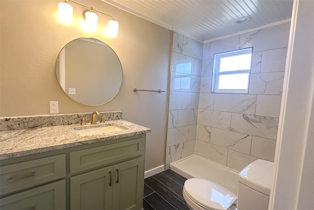 bathroom featuring a tile shower, hardwood / wood-style flooring, vanity, and toilet