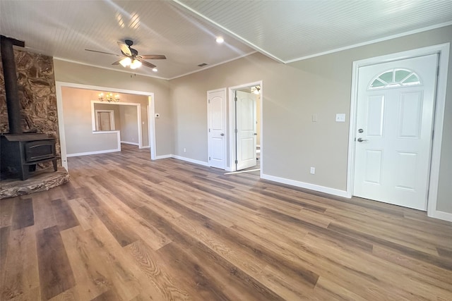 unfurnished living room featuring a wood stove, ceiling fan, ornamental molding, and hardwood / wood-style flooring