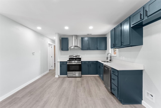 kitchen with stainless steel appliances, light wood-style floors, wall chimney range hood, and a sink