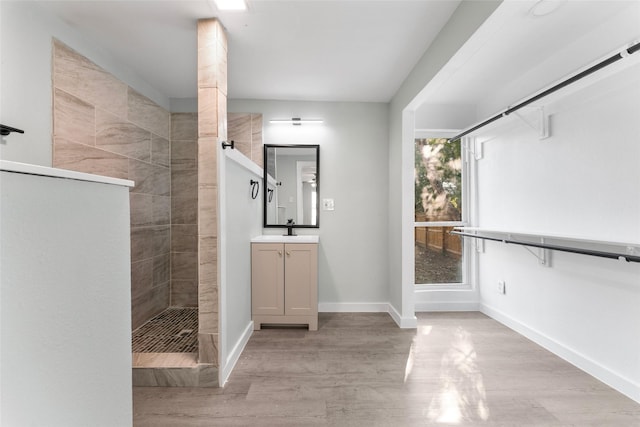 full bath featuring vanity, wood finished floors, baseboards, and walk in shower