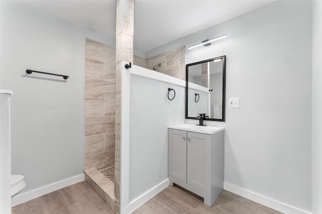 full bathroom featuring baseboards, wood finished floors, vanity, and a walk in shower