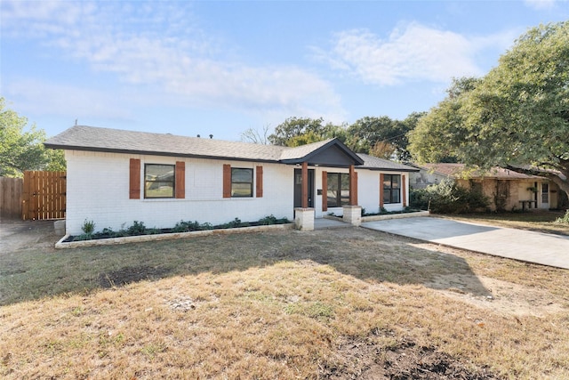 ranch-style home with brick siding, a front lawn, and fence