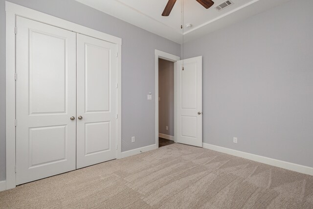 unfurnished bedroom featuring light carpet, ceiling fan, and a closet