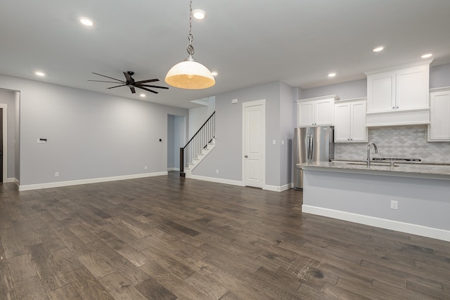 kitchen with stainless steel fridge, decorative light fixtures, dark hardwood / wood-style floors, light stone countertops, and white cabinets