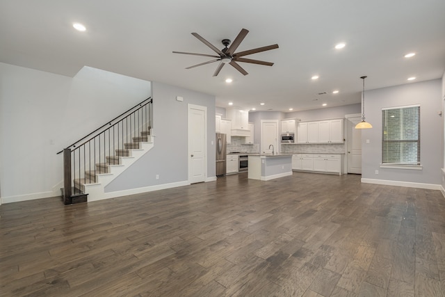 unfurnished living room with ceiling fan, sink, and dark hardwood / wood-style flooring