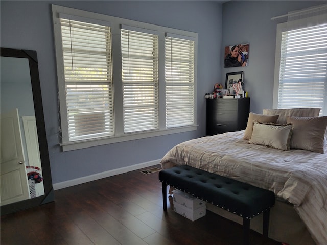 bedroom featuring multiple windows and dark hardwood / wood-style flooring