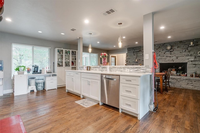 kitchen featuring white cabinetry, dishwasher, pendant lighting, light hardwood / wood-style floors, and a fireplace