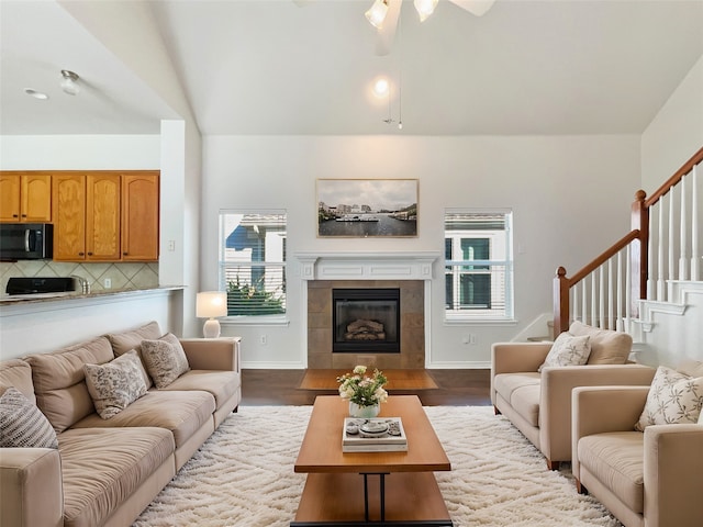 living room with light hardwood / wood-style flooring, lofted ceiling, ceiling fan, and a tile fireplace