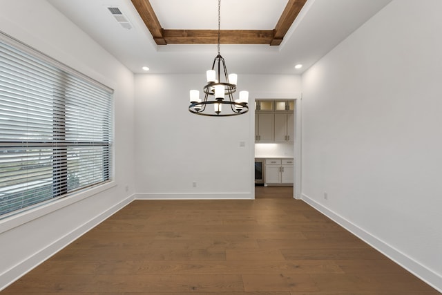 unfurnished dining area with dark wood-type flooring, a notable chandelier, a tray ceiling, and beverage cooler