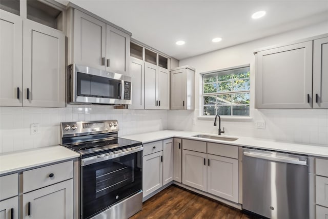 kitchen featuring sink, dark wood-type flooring, gray cabinets, appliances with stainless steel finishes, and tasteful backsplash