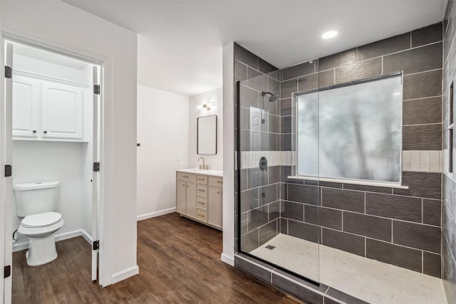 bathroom with vanity, hardwood / wood-style floors, toilet, and tiled shower