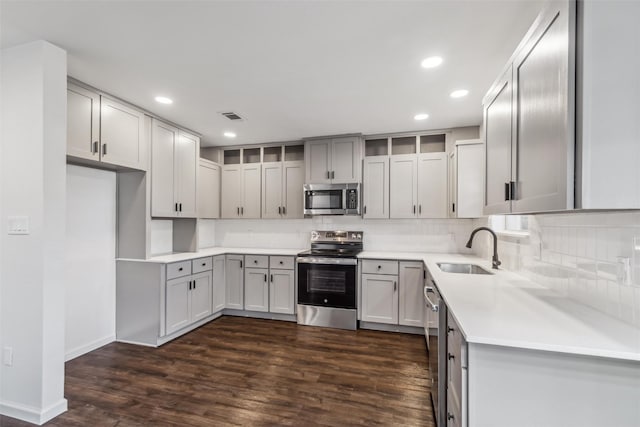 kitchen featuring dark wood-type flooring, stainless steel appliances, sink, and decorative backsplash