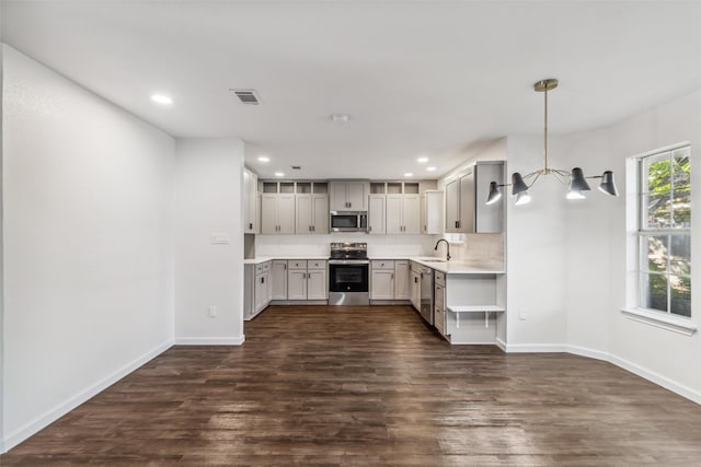 kitchen with appliances with stainless steel finishes, sink, dark hardwood / wood-style flooring, hanging light fixtures, and a notable chandelier