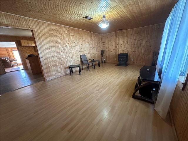 unfurnished room with wood walls, a wood stove, and hardwood / wood-style floors