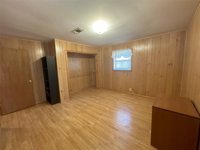 unfurnished bedroom with wooden walls, hardwood / wood-style flooring, and a textured ceiling